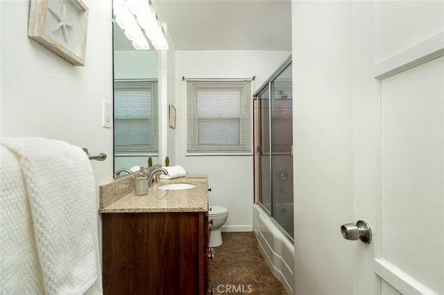 bathroom with vanity, toilet, and combined bath / shower with glass door