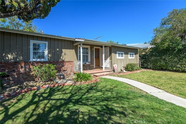 ranch-style home with a porch, board and batten siding, brick siding, and a front lawn