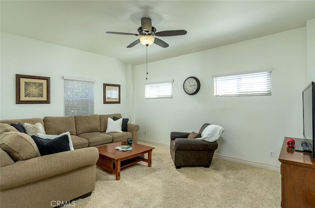 living area with baseboards, light colored carpet, and a ceiling fan