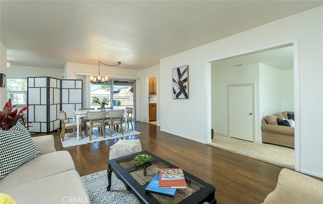 living room with dark wood-style floors, baseboards, and an inviting chandelier