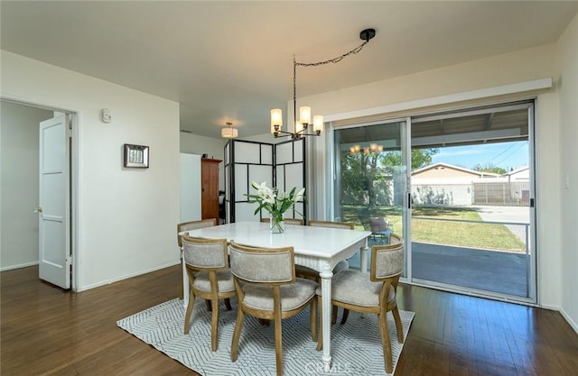 dining space featuring baseboards, dark wood-type flooring, and an inviting chandelier