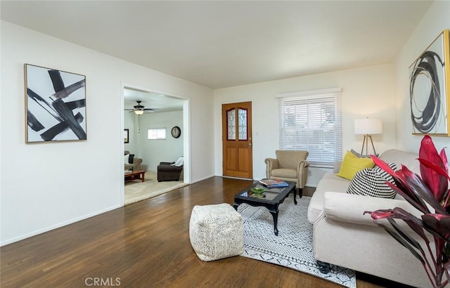 living area with a ceiling fan, wood finished floors, and baseboards