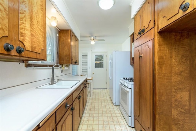 kitchen with brown cabinets, light floors, gas range gas stove, and a sink