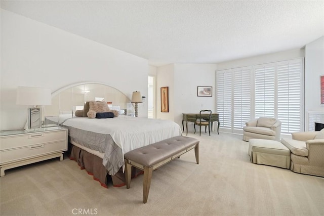 bedroom with a textured ceiling, multiple windows, and light carpet