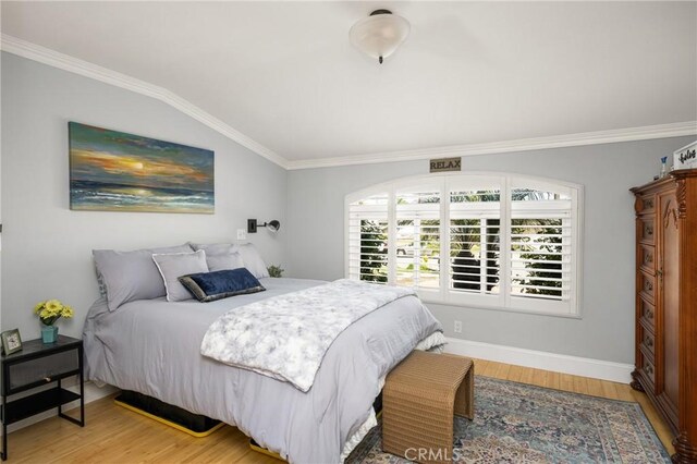 bedroom with light wood-type flooring, baseboards, ornamental molding, and vaulted ceiling