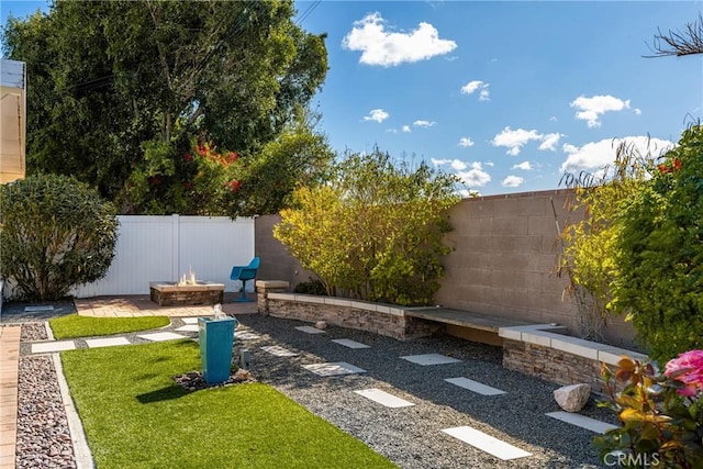 view of yard featuring a patio, a fire pit, and a fenced backyard