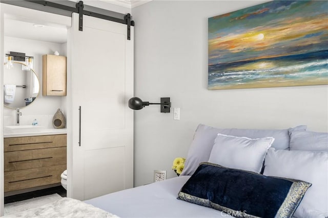 bedroom featuring a barn door, connected bathroom, water heater, and a sink