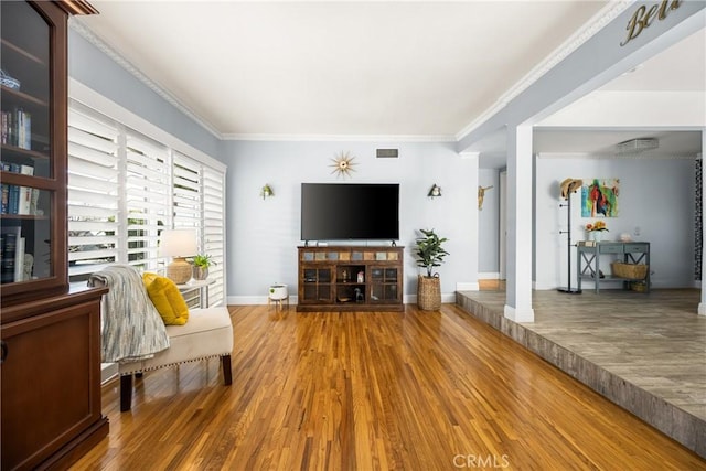 living room featuring baseboards, wood finished floors, visible vents, and ornamental molding