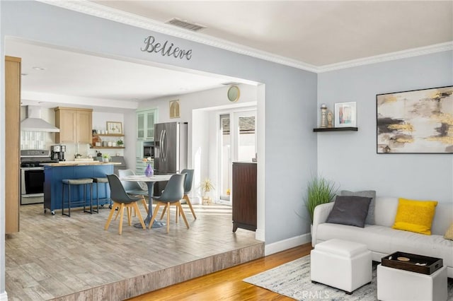 living room with crown molding, baseboards, visible vents, and light wood-type flooring