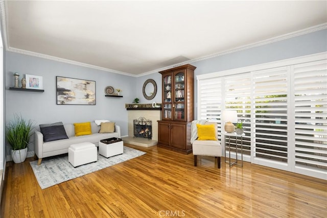 living room with ornamental molding, wood finished floors, and a lit fireplace