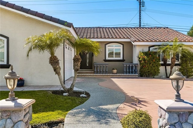 exterior space with a tiled roof, an attached garage, and stucco siding