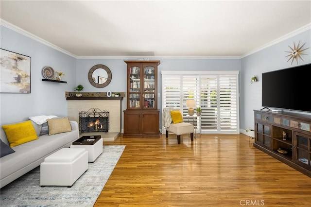 living room featuring a fireplace, wood finished floors, baseboards, and ornamental molding