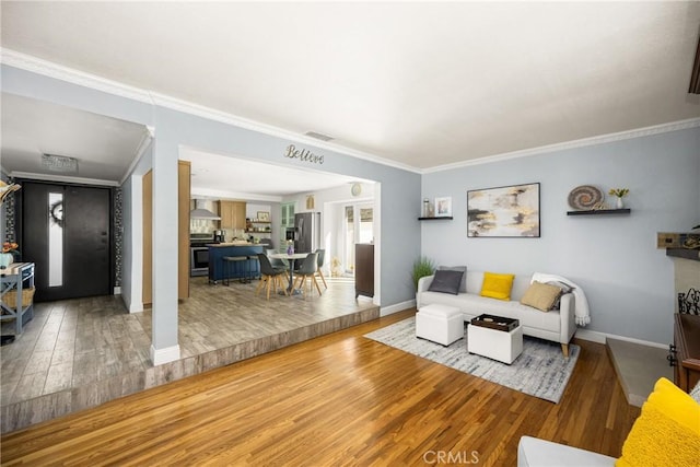 living room featuring baseboards, crown molding, and light wood finished floors