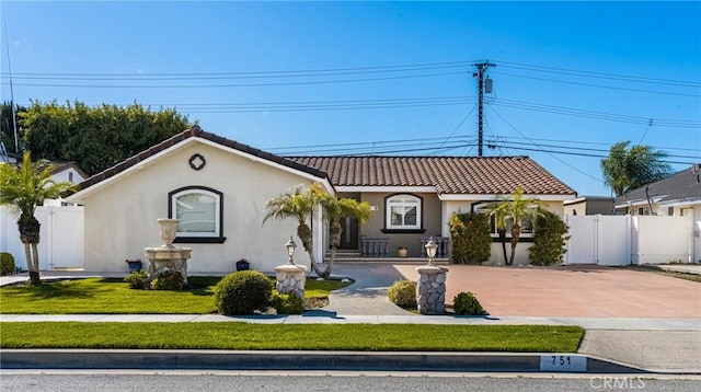 mediterranean / spanish house featuring a tiled roof, fence, driveway, and stucco siding