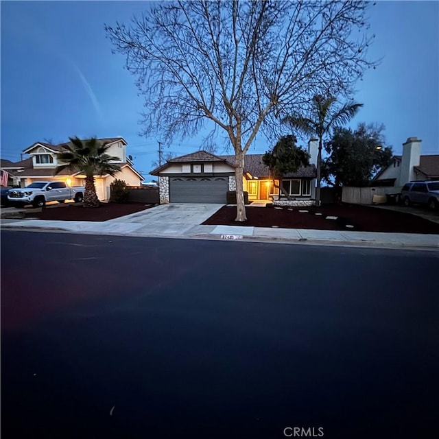 view of front of property featuring an attached garage, driveway, and fence