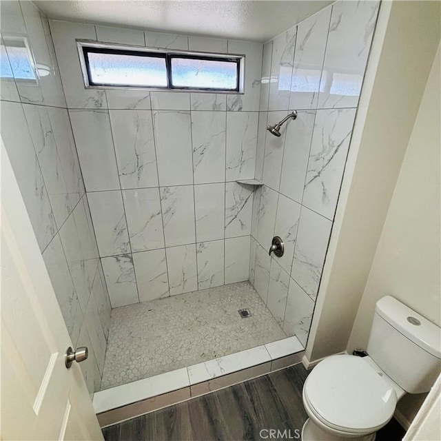 full bathroom with a shower stall, toilet, and wood finished floors