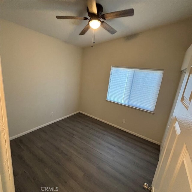 unfurnished room featuring baseboards, dark wood-type flooring, and ceiling fan