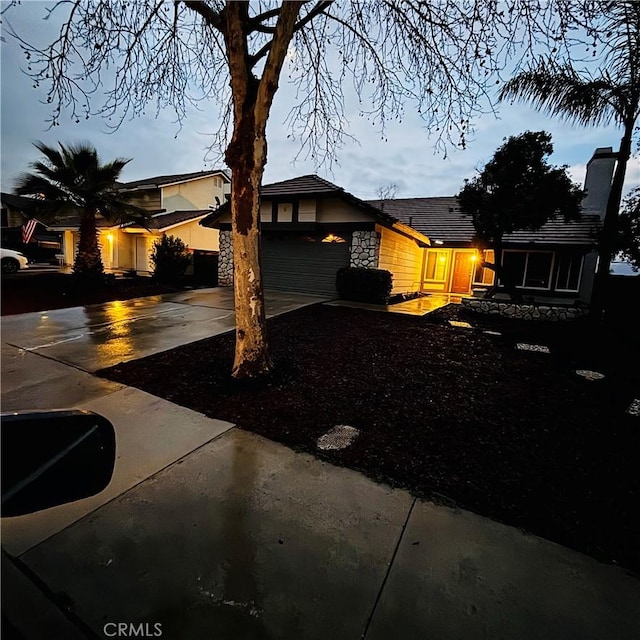 view of front of property featuring concrete driveway, an attached garage, and stone siding