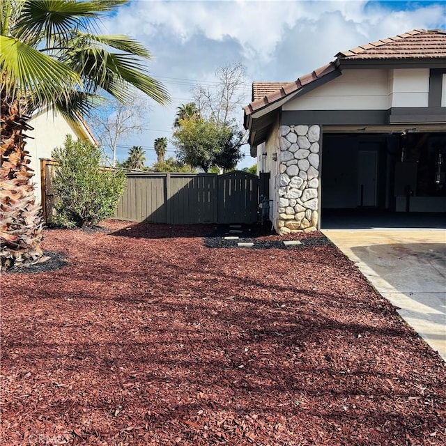 view of yard with concrete driveway, a gate, fence, and a garage