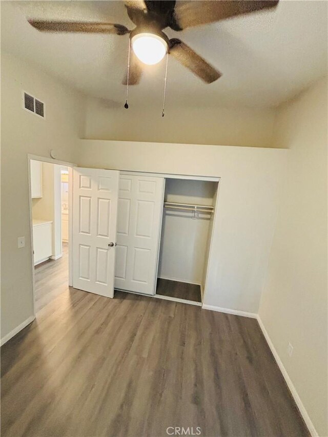 unfurnished bedroom with a closet, visible vents, baseboards, and wood finished floors