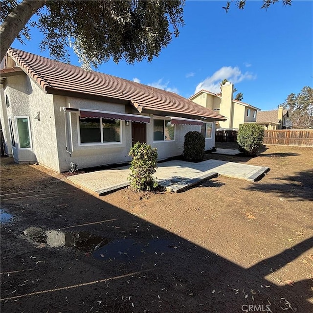 rear view of property with a patio, a tiled roof, fence, and stucco siding