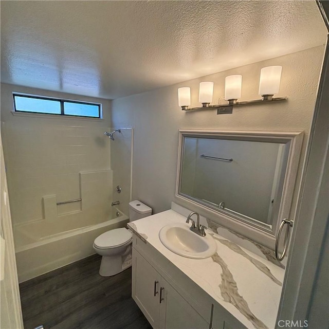 bathroom featuring toilet, a textured ceiling, wood finished floors, washtub / shower combination, and vanity