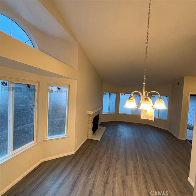 unfurnished living room with a stone fireplace, an inviting chandelier, dark wood-style floors, and lofted ceiling