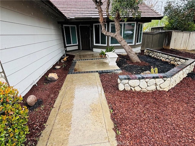 property entrance with fence and a tile roof