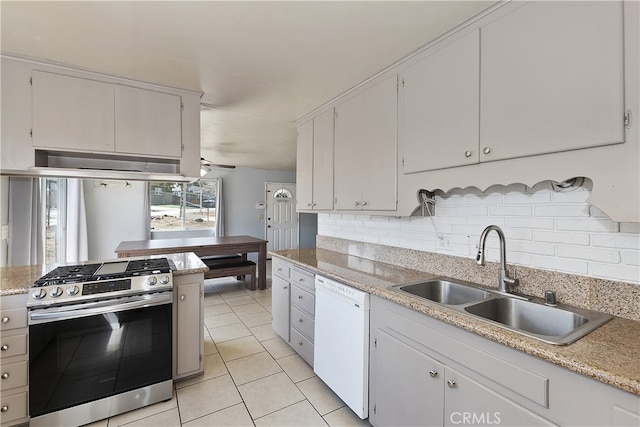 kitchen featuring a sink, under cabinet range hood, backsplash, white dishwasher, and gas range