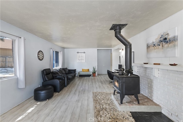 living room featuring a wood stove, wood finished floors, and a textured ceiling