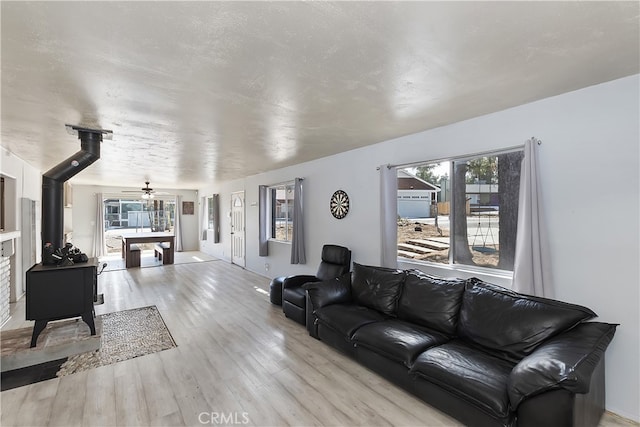 living area with a textured ceiling, light wood finished floors, and ceiling fan