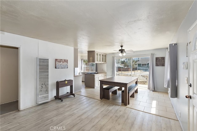 dining area featuring a textured ceiling, light wood-type flooring, a heating unit, and ceiling fan