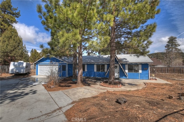 view of front of home with concrete driveway, a garage, and fence