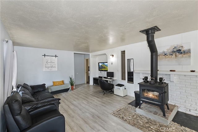 living area featuring a textured ceiling, light wood-style flooring, and a wood stove