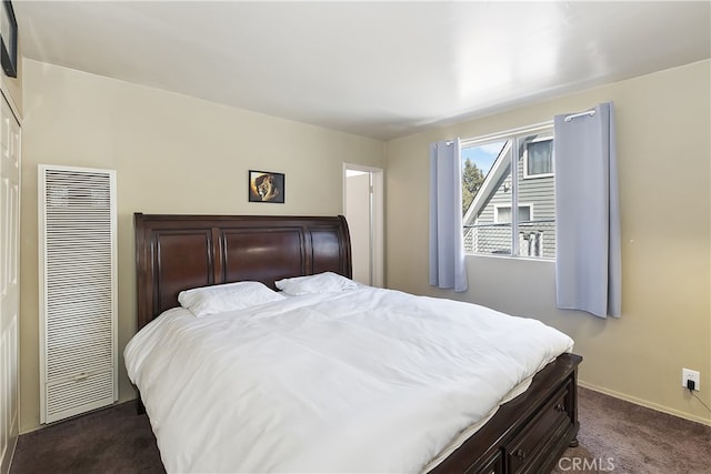 bedroom with baseboards, dark colored carpet, and a heating unit