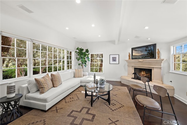 living area with wood finished floors, visible vents, recessed lighting, a warm lit fireplace, and beamed ceiling