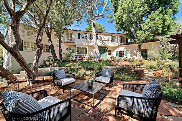 rear view of property with outdoor lounge area, a balcony, a patio area, and stucco siding