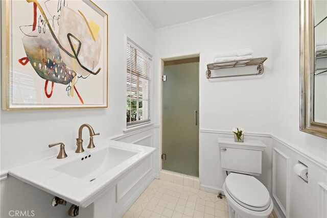 full bathroom with tile patterned flooring, crown molding, toilet, a stall shower, and a sink