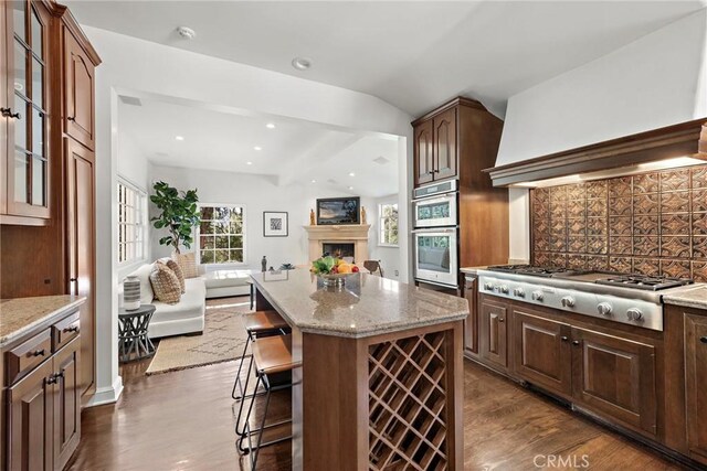 kitchen with tasteful backsplash, open floor plan, a center island, appliances with stainless steel finishes, and custom exhaust hood