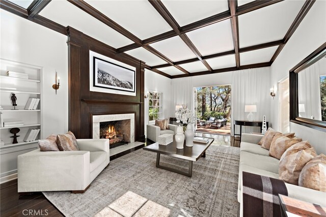 living room with beamed ceiling, coffered ceiling, a fireplace, and wood finished floors