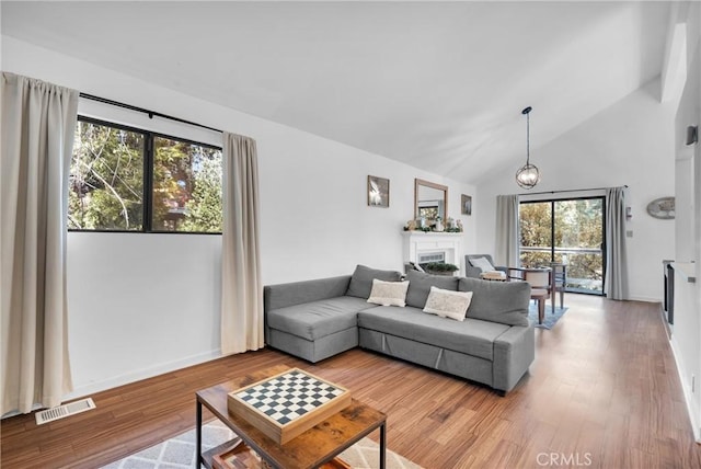 living room with baseboards, wood finished floors, visible vents, and high vaulted ceiling