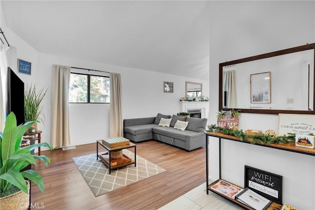 living area with a fireplace, lofted ceiling, and wood finished floors