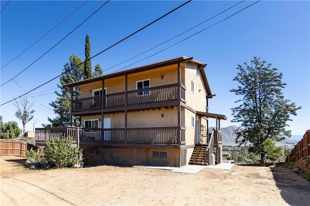 back of house with stucco siding, stairway, and fence