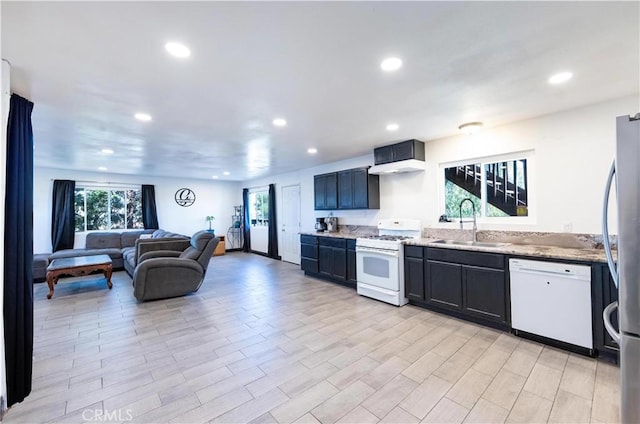 kitchen with a sink, light stone counters, open floor plan, recessed lighting, and white appliances