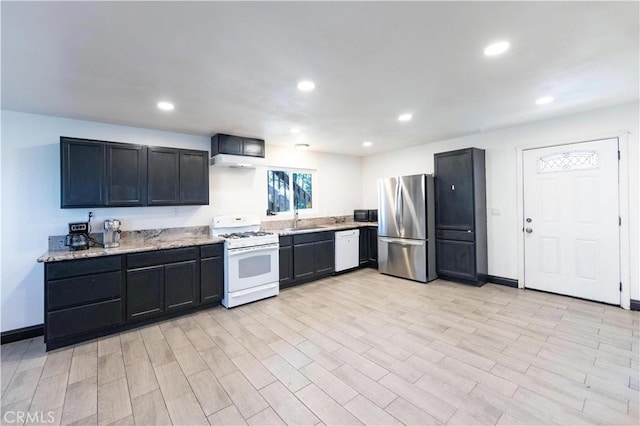 kitchen with white appliances, light stone countertops, recessed lighting, a sink, and light wood-type flooring