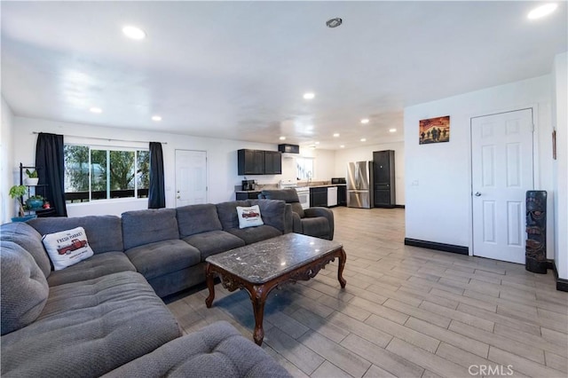 living room with recessed lighting, baseboards, and light wood-style floors