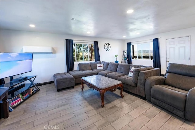 living area featuring light wood finished floors, plenty of natural light, recessed lighting, and a wall unit AC