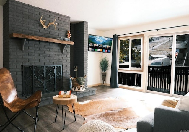 living area with a brick fireplace, wood finished floors, and baseboards