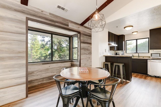 dining area with wooden walls, light wood-style floors, and visible vents