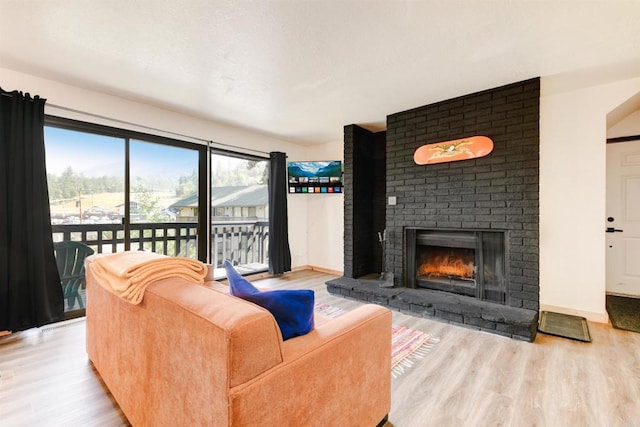 living room featuring a brick fireplace, wood finished floors, and baseboards